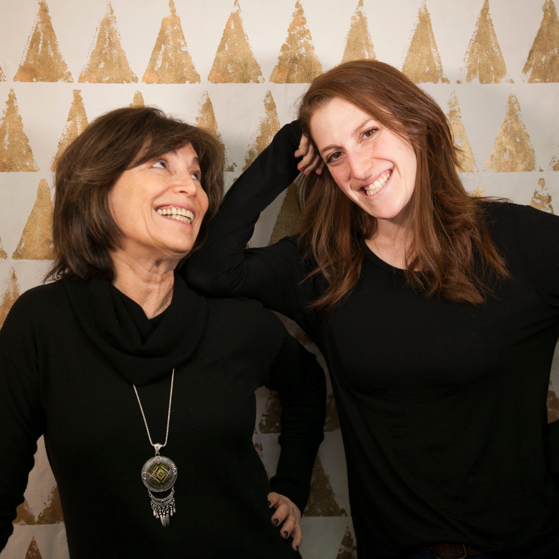 Jill and Jackie laughing together in front of their gold triangle mural