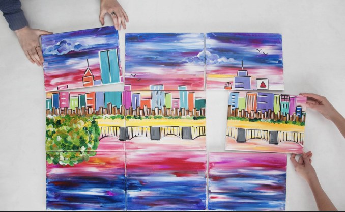 A team assembling a large collaborative painting made of individual canvases